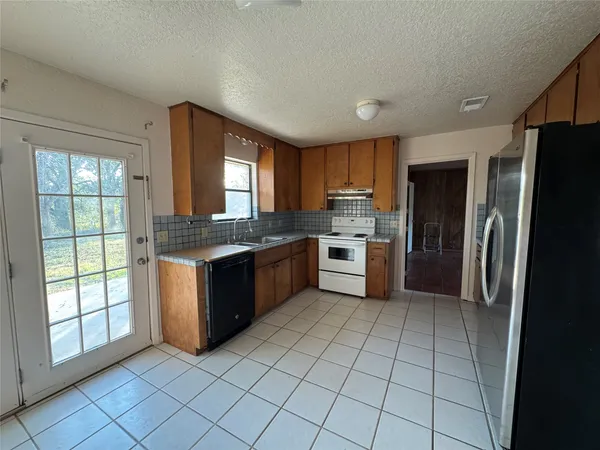 a large kitchen with a stove a sink dishwasher a refrigerator and cabinets