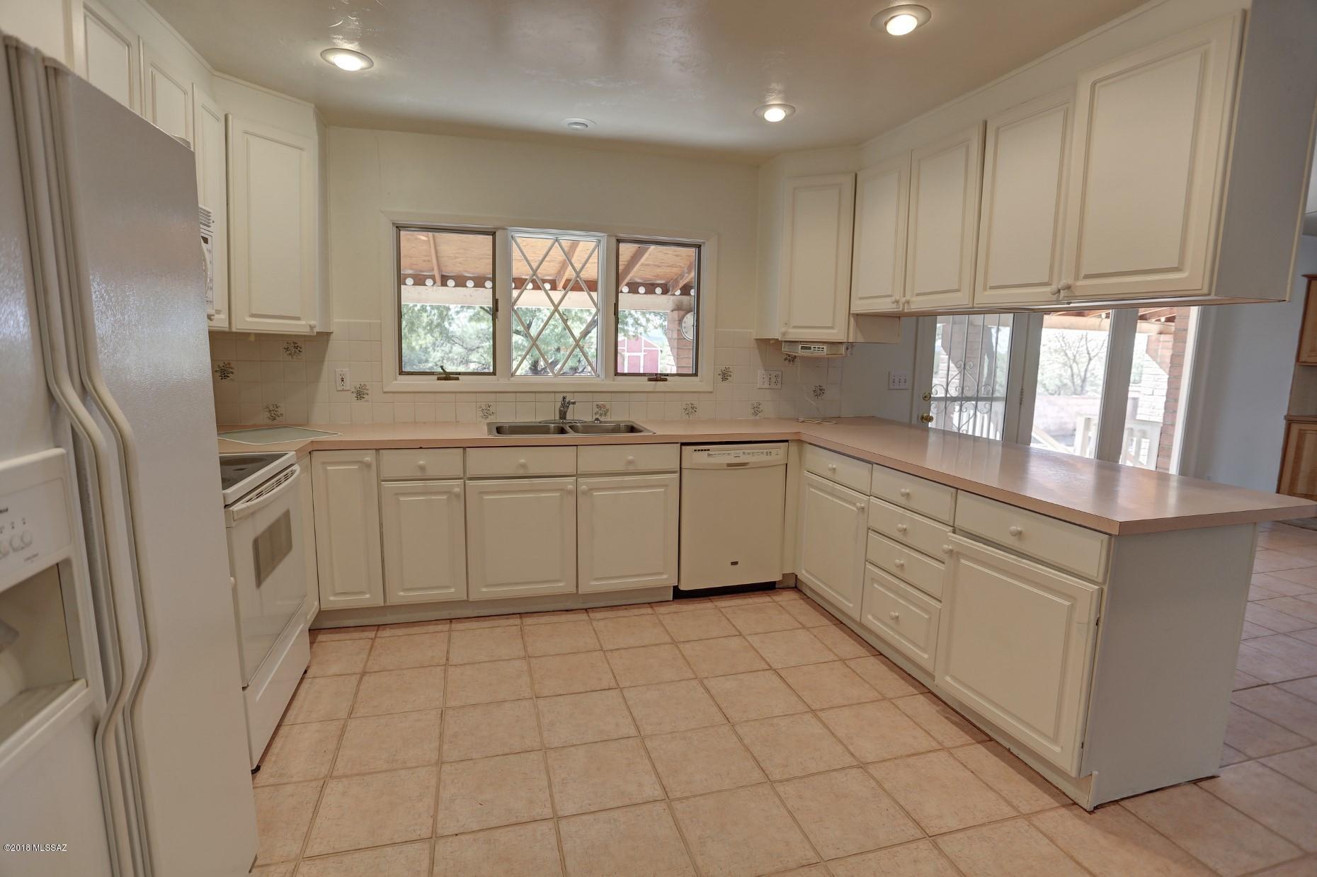 5851 South Avra Road Tucson, AZ 85735 - Photo 6 of 46 a large white kitchen with a sink a refrigerator and window