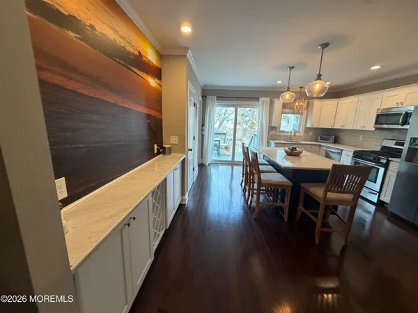 a kitchen with stainless steel appliances kitchen island granite countertop lots of wooden cabinets a dining table and chairs