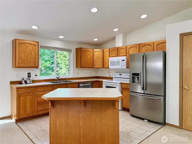 a kitchen with stainless steel appliances granite countertop a refrigerator a sink a stove with wooden cabinets