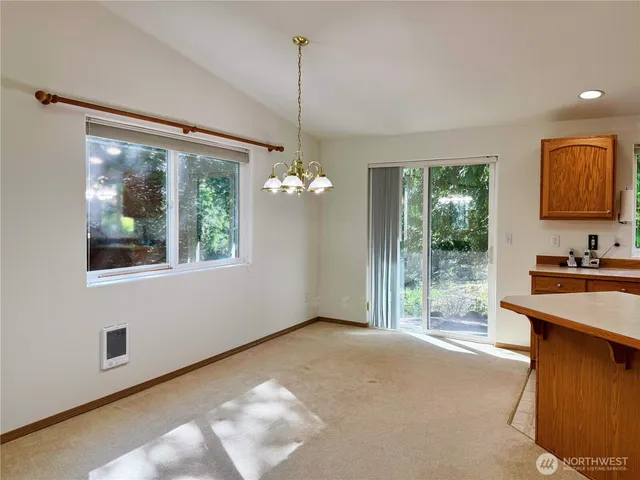 a view of an empty room with a window and kitchen view
