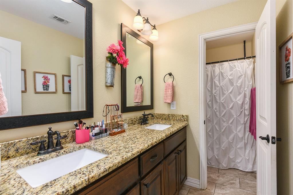 203 Saddle Ridge Court Springtown, TX 76082 - Photo 25 of 34 a bathroom with a granite countertop sink a large mirror and a shower