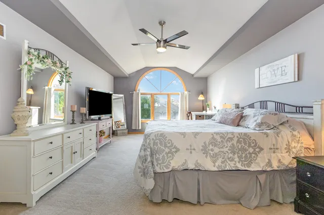 a spacious bedroom with a bed and a flat screen tv