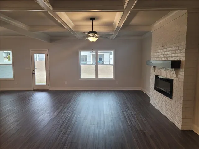 an empty room with wooden floor fireplace and windows