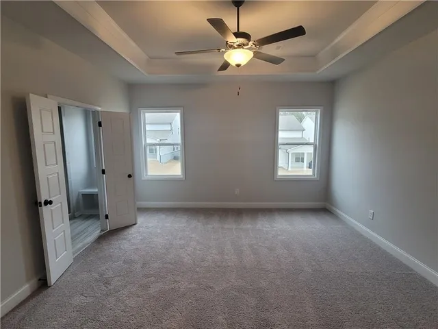 an empty room with chandelier fan and windows