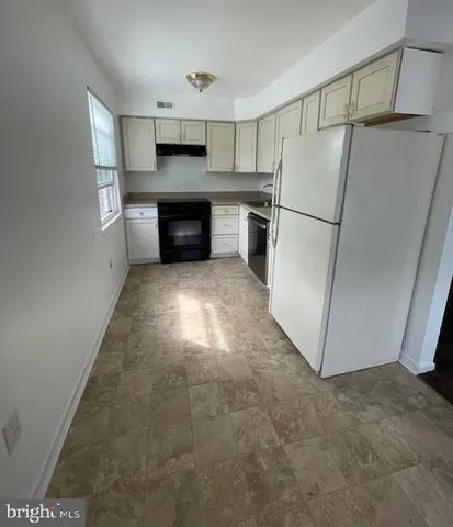 a kitchen with refrigerator and white cabinets