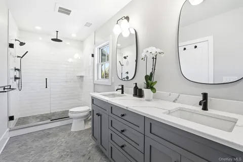 a bathroom with a double vanity sink mirror and toilet