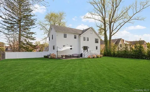 a view of a white house with a big yard and large trees