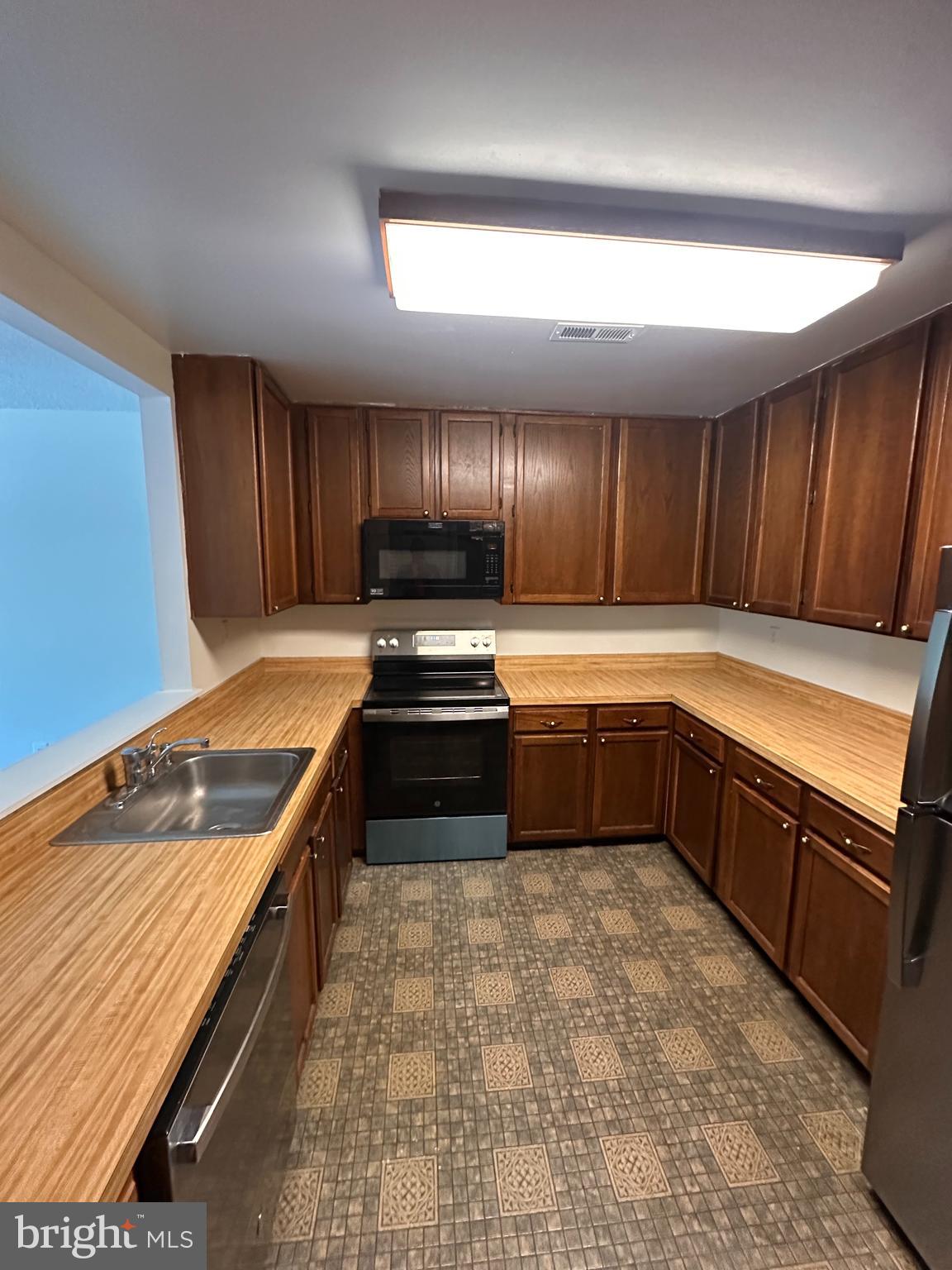 6937 Mayfair Terrace Laurel, MD 20707 - Photo 10 of 36 a kitchen with wooden cabinets and stainless steel appliances