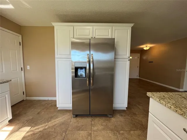 a view of a refrigerator in kitchen and an empty room