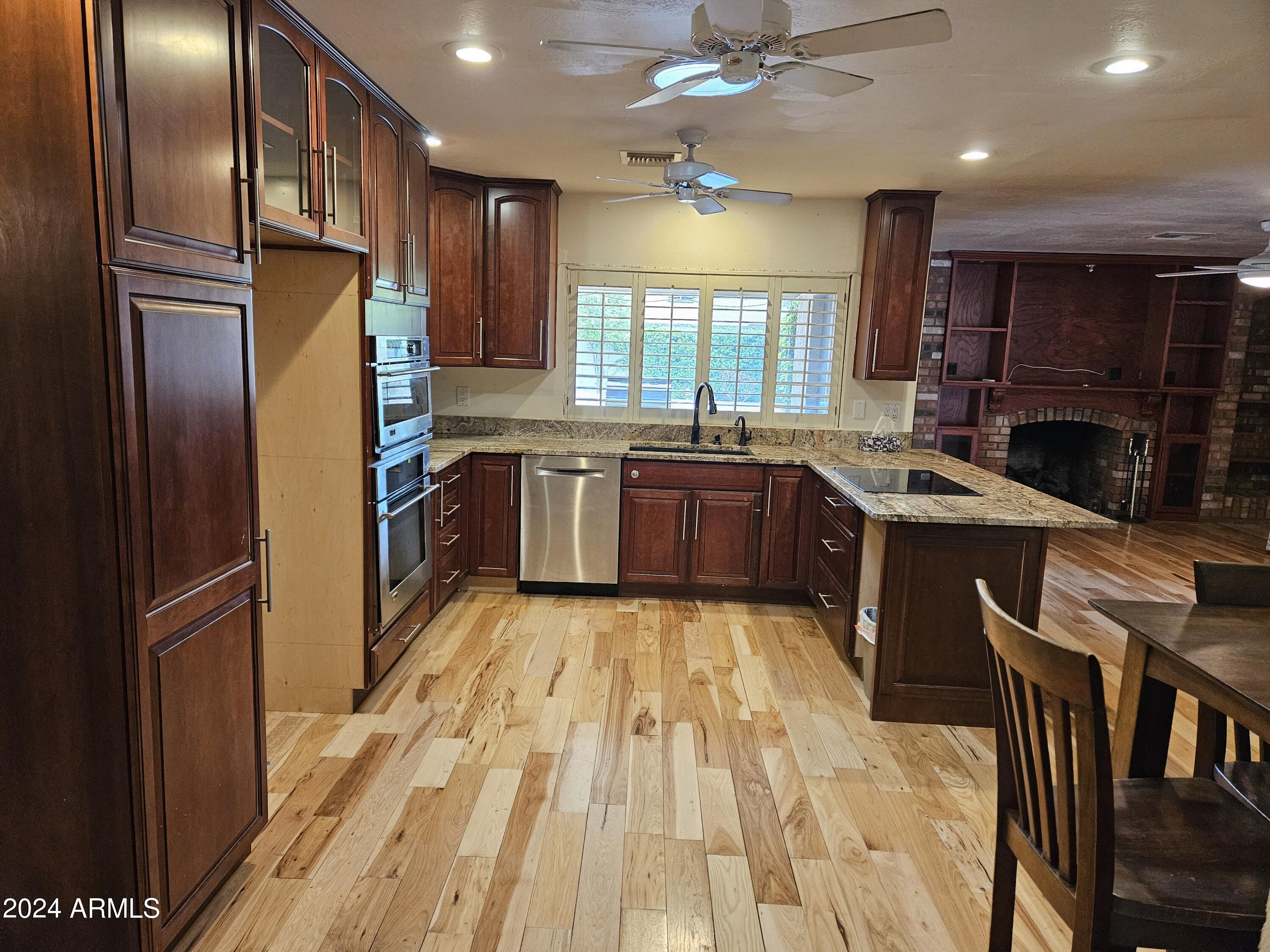 948 East Grandview Road Phoenix, AZ 85022 - Photo 13 of 43 a large kitchen with stainless steel appliances granite countertop a refrigerator a sink dishwasher a stove and a dining table with wooden floor