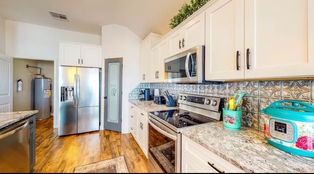 a kitchen with stainless steel appliances granite countertop a stove a sink and a refrigerator