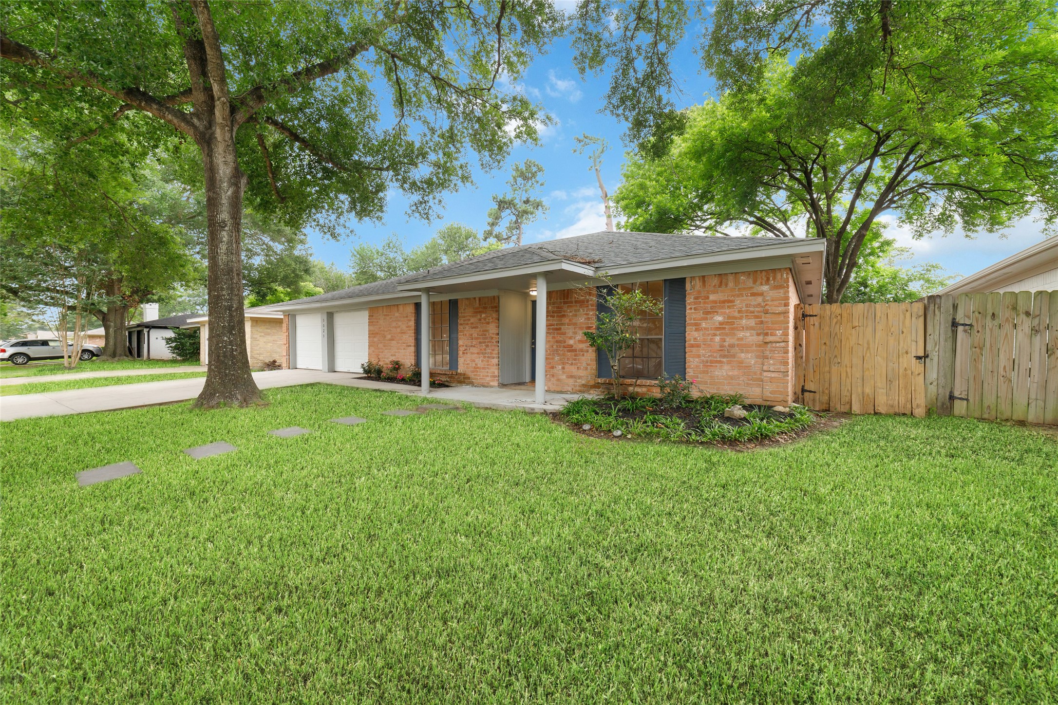 5023 Monteith Drive Spring, TX 77373 - Photo 2 of 20 Angled view of the front showcasing the cozy porch, shaded by mature trees, with windows that brighten the space and add to the home’s warm, welcoming feel.