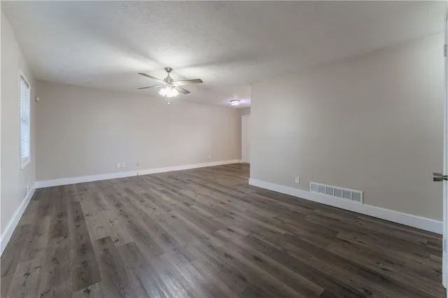 an empty room with wooden floor and a ceiling fan