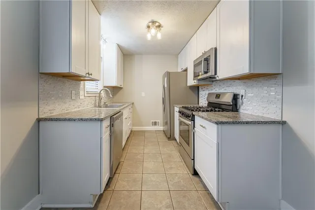 a kitchen with stainless steel appliances granite countertop a sink and dishwasher a stove top oven with white cabinets