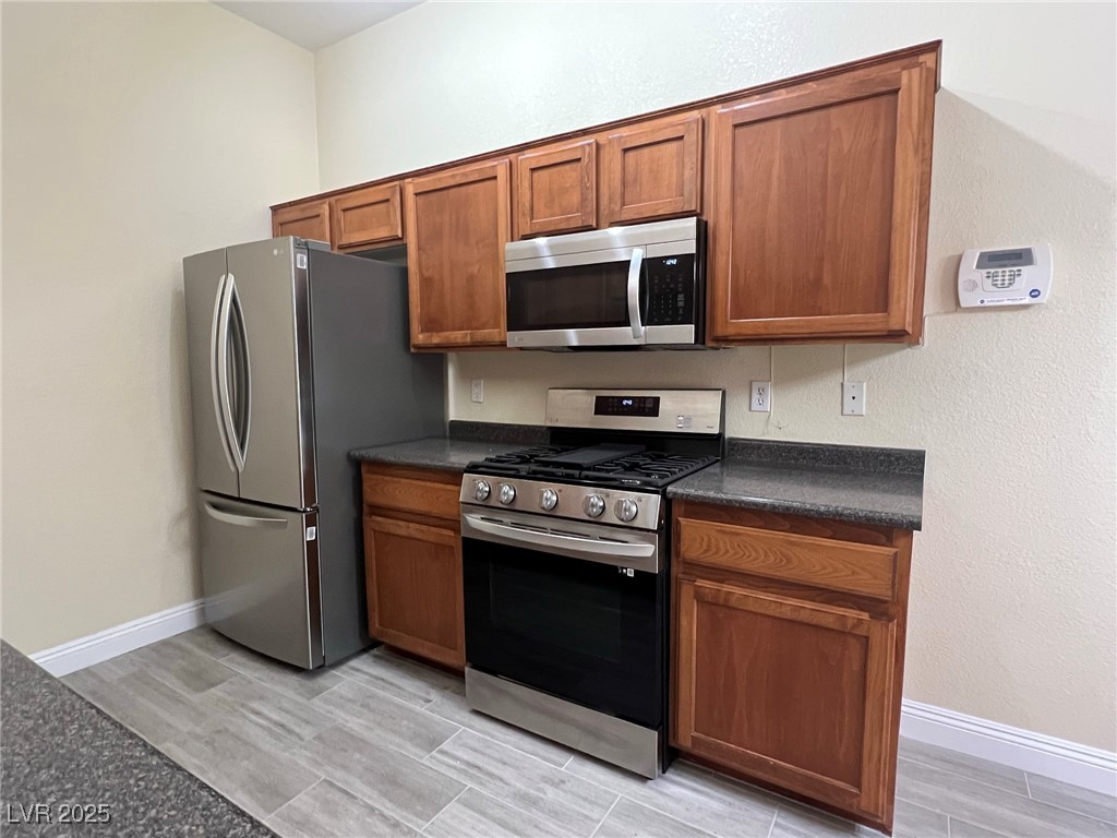 8805 Jeffreys Street, Unit 1111 Las Vegas, NV 89123 - Photo 11 of 35 Kitchen with appliances with stainless steel finishes, wood tiled floors, brown cabinets, and a textured wall