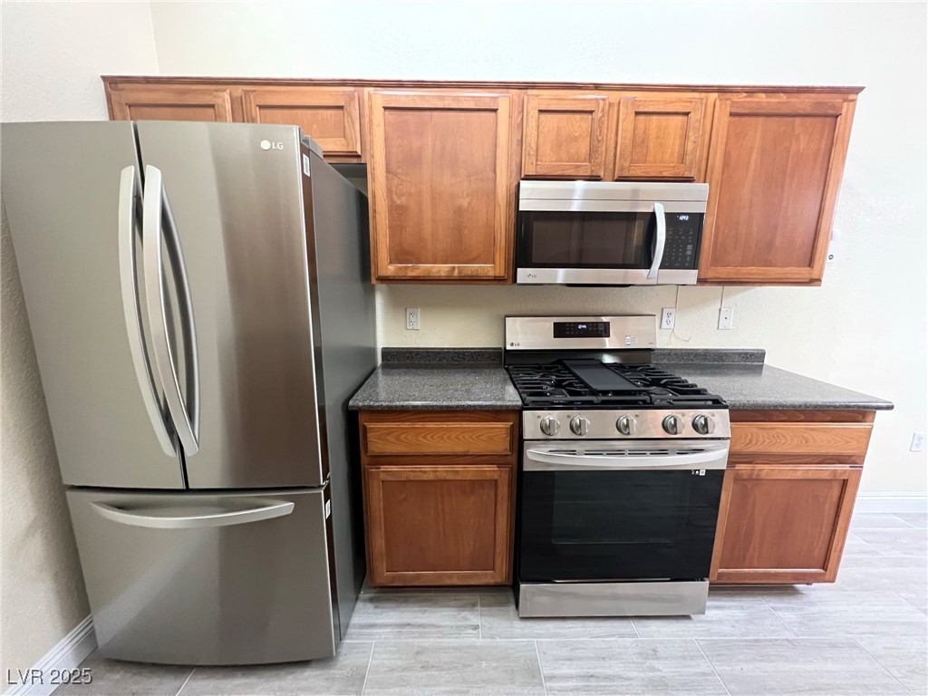 8805 Jeffreys Street, Unit 1111 Las Vegas, NV 89123 - Photo 14 of 35 Kitchen featuring appliances with stainless steel finishes, brown cabinetry, and dark stone counters
