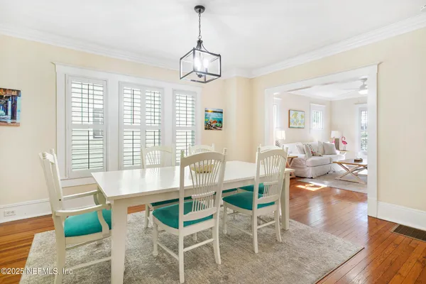 a dining room with wooden floor and a chandelier