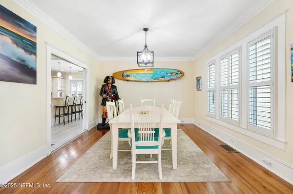 a dining room with wooden floor a chandelier a wooden table and chairs