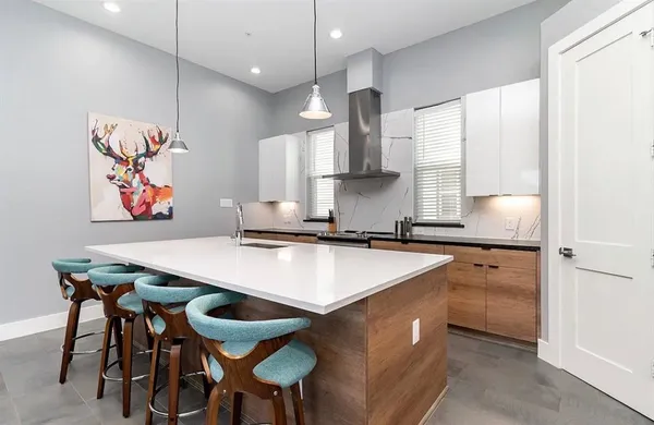 a kitchen with stainless steel appliances granite countertop a sink a stove a refrigerator and island with wooden floor