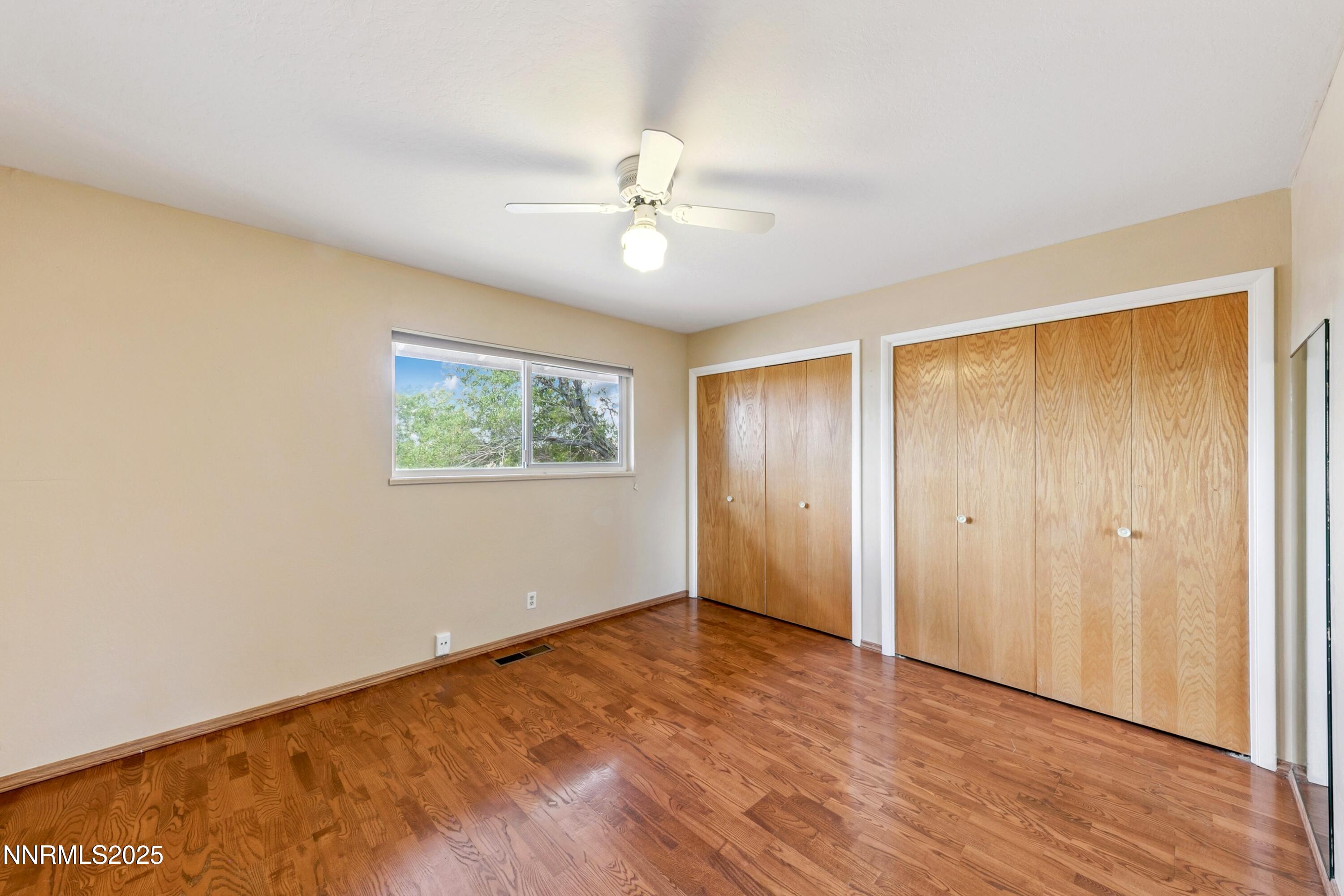 3550 Lone Tree Lane Reno, NV 89511 - Photo 32 of 40 an empty room with wooden floor chandelier fan and windows