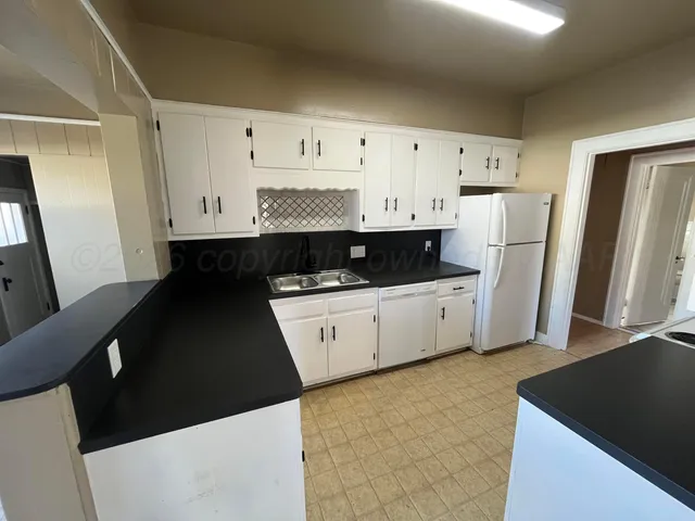 a kitchen with stainless steel appliances a refrigerator a sink a stove and white cabinets