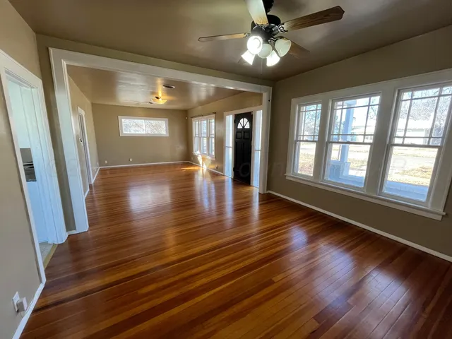 a view of an empty room with wooden floor and a window