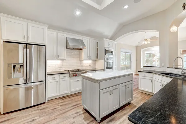 a kitchen with granite countertop white cabinets and white appliances