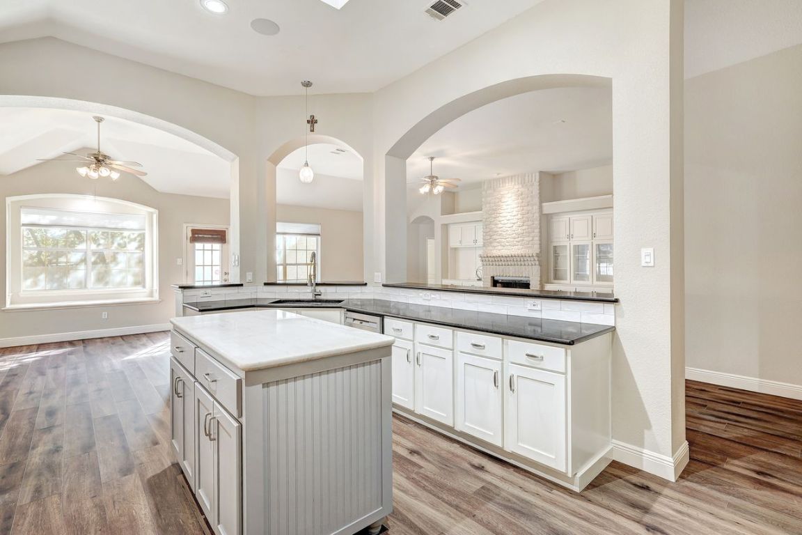301 Rim Rock Drive Georgetown, TX 78628 - Photo 40 of 40 Kitchen with ceiling fan, white cabinetry, open floor plan, decorative light fixtures, and a kitchen island