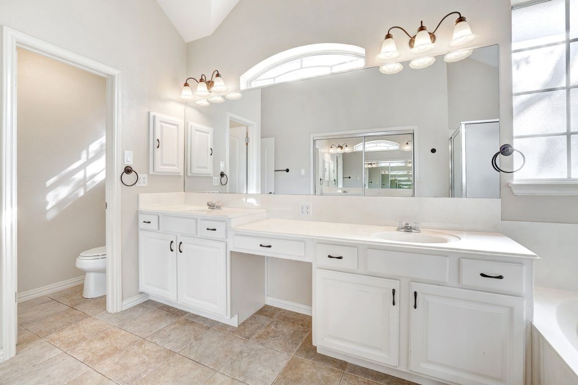 301 Rim Rock Drive Georgetown, TX 78628 - Photo 23 of 40 Bathroom featuring a garden tub, double vanity, healthy amount of natural light, lofted ceiling, and light tile patterned floors