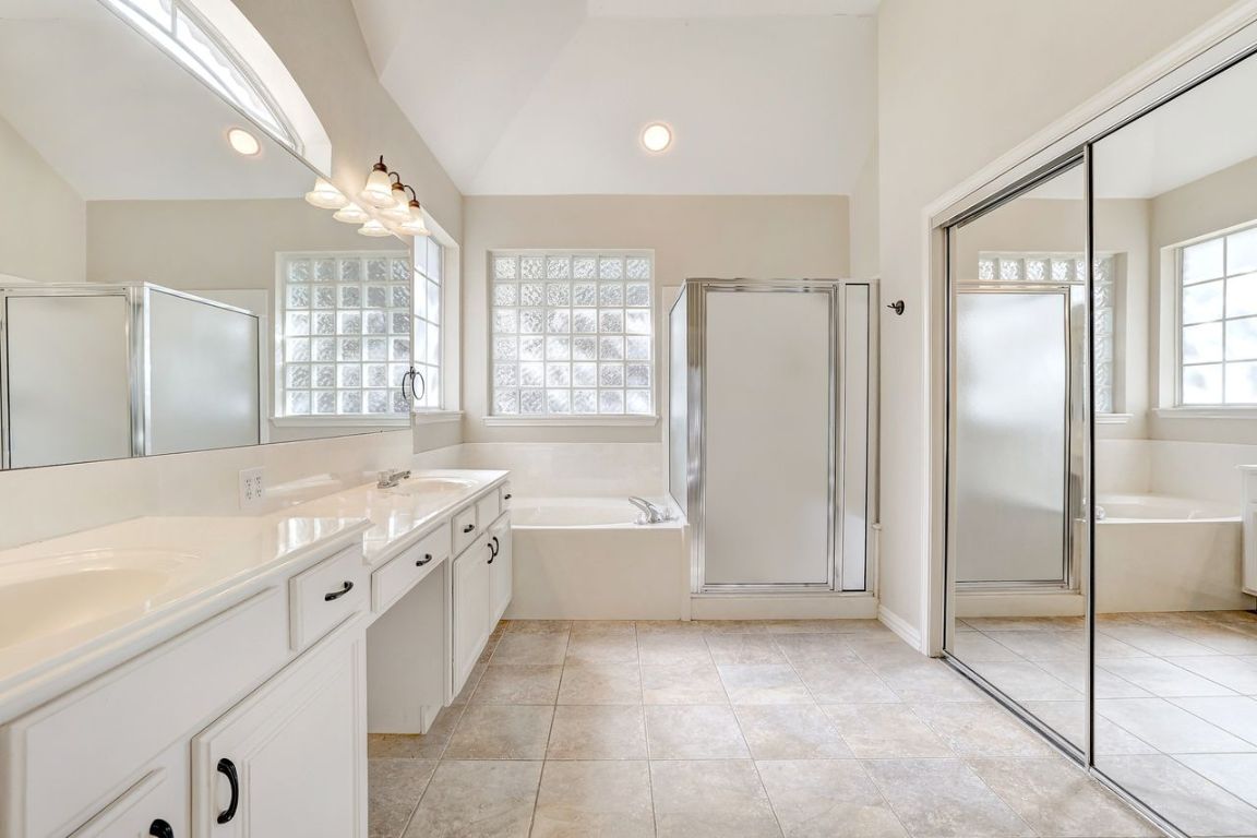 301 Rim Rock Drive Georgetown, TX 78628 - Photo 24 of 40 Bathroom with a bath, lofted ceiling, double vanity, a separate shower, and light tile patterned floors