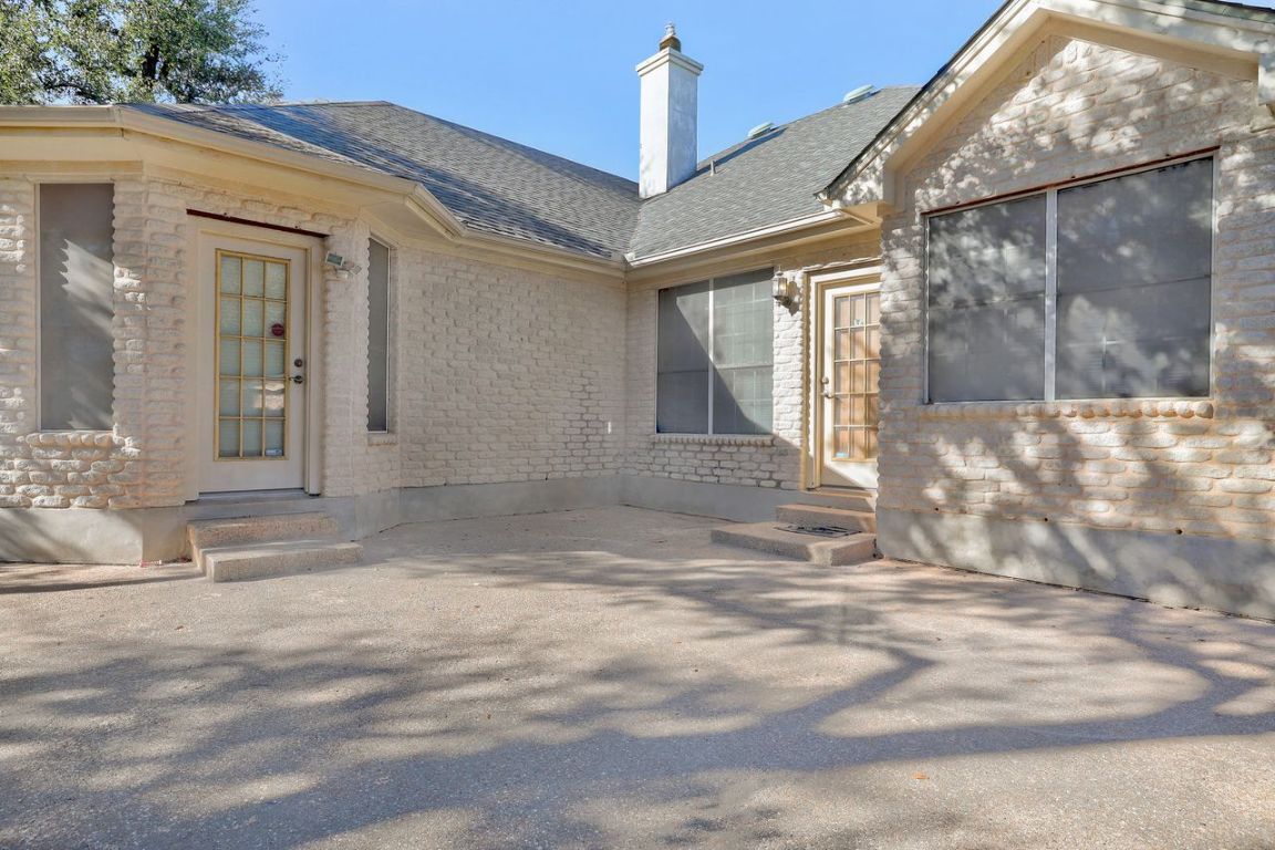 301 Rim Rock Drive Georgetown, TX 78628 - Photo 39 of 40 Entrance to back door with a patio area, a chimney, a shingled roof, and stone siding