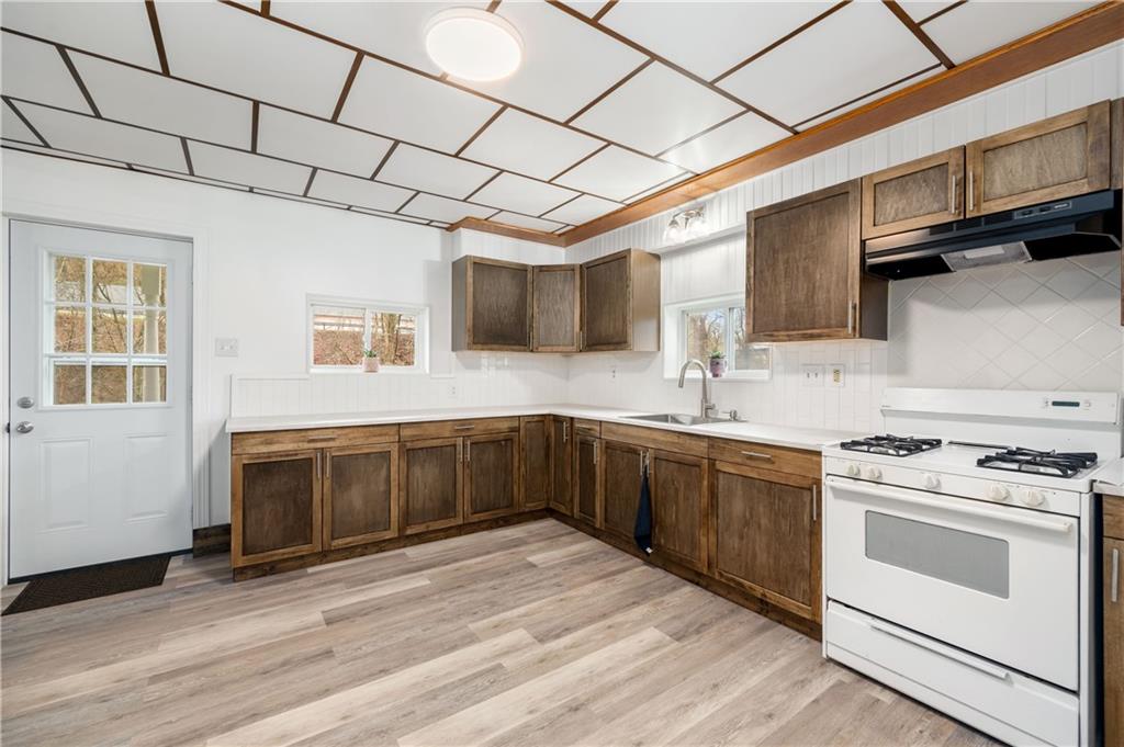 140 Whitestown Road Lyndora, PA 16045 - Photo 12 of 29 a kitchen with stainless steel appliances granite countertop a sink a stove top oven and wooden floors
