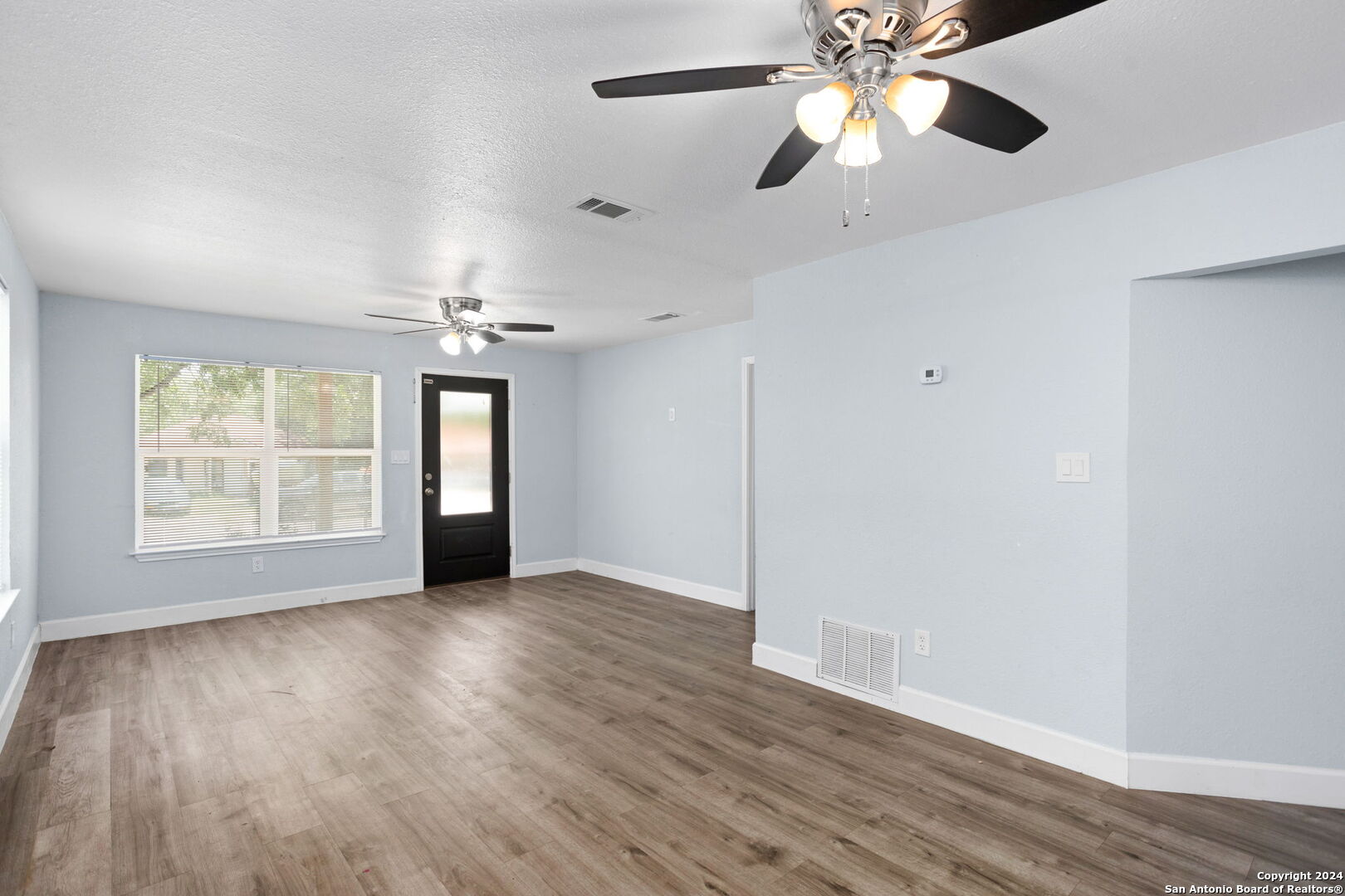 113 Vista Road San Antonio, TX 78210 - Photo 4 of 17 an empty room with wooden floor chandelier fan and windows