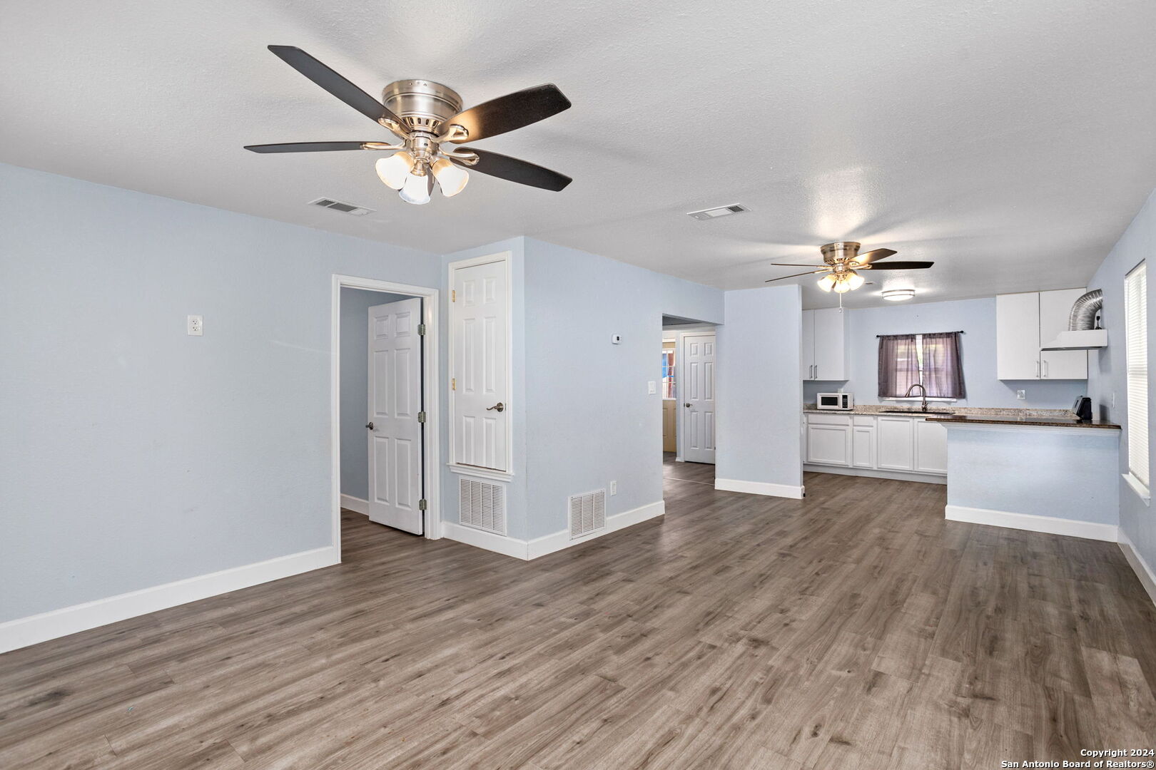 113 Vista Road San Antonio, TX 78210 - Photo 5 of 17 a view of an empty room with wooden floor and a ceiling fan