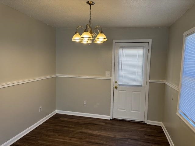 205 Reno Avenue Memphis, TN 38107 - Photo 8 of 17 Unfurnished dining area with a chandelier, a textured ceiling, dark wood-type flooring, and baseboards