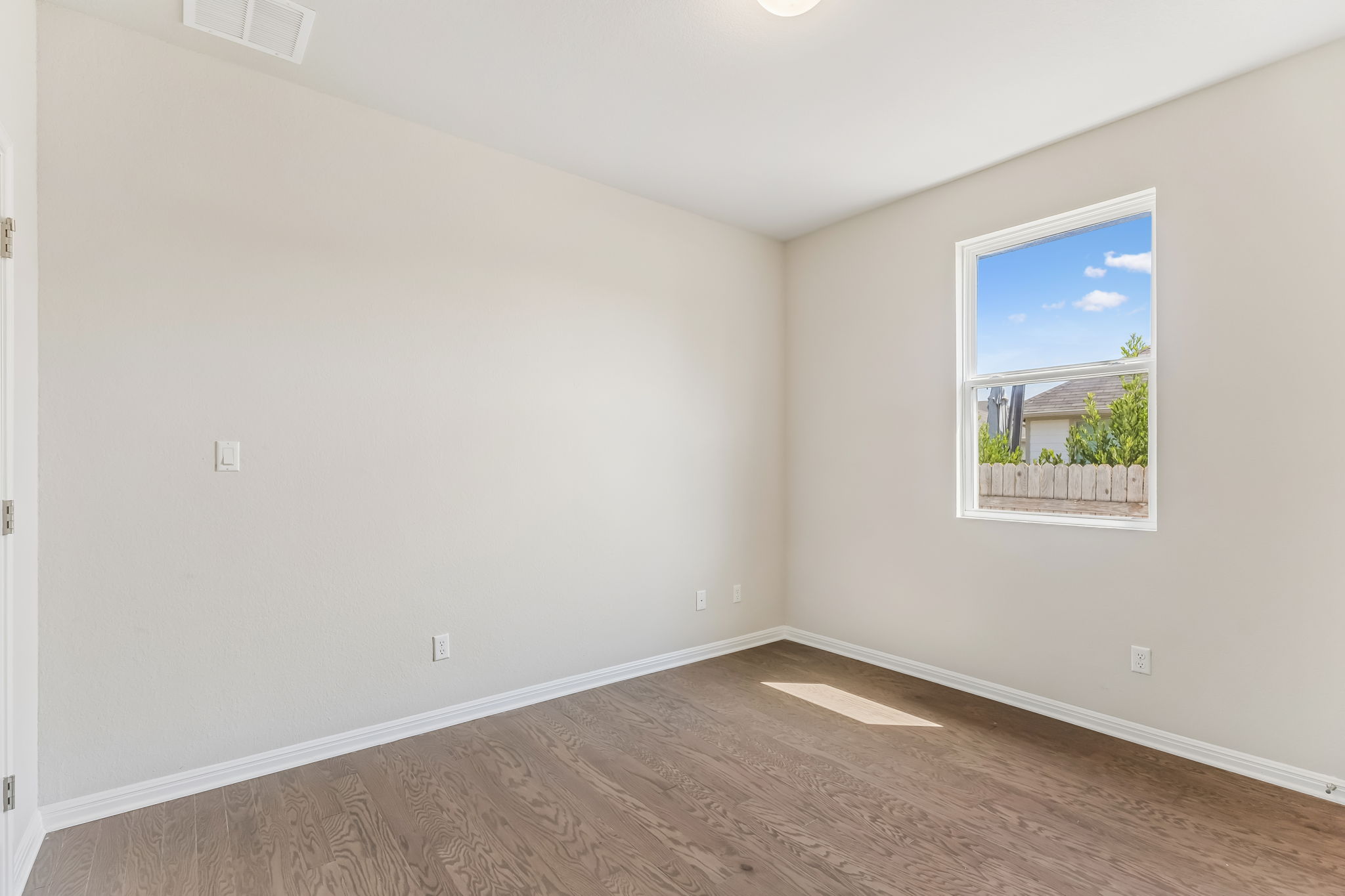 4009 Milano River Road Hutto, TX 78634 - Photo 17 of 40 Rich hardwood floors and classic baseboards anchor this versatile bedroom space.