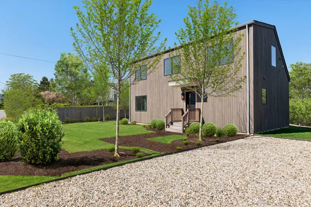 a backyard of a house with plants and large tree