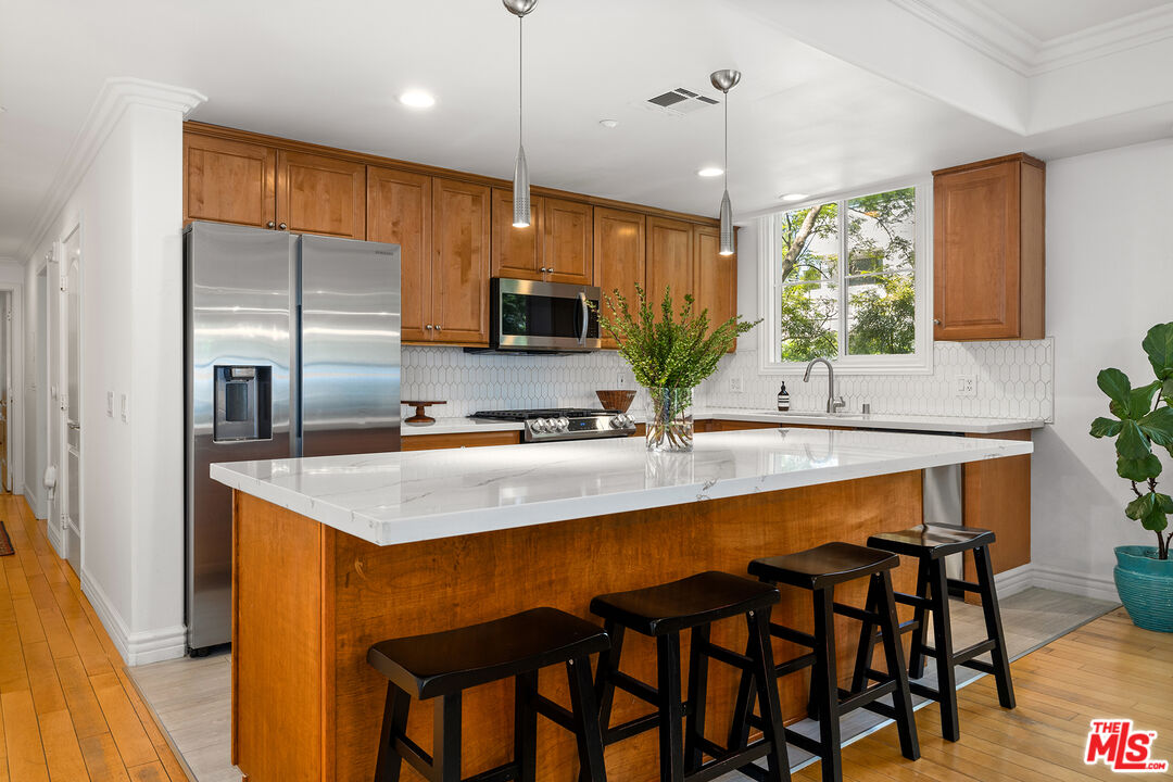 1601 South Bentley Avenue, Unit 201 Los Angeles, CA 90025 - Photo 8 of 39 a kitchen with kitchen island granite countertop a table chairs sink and stove top oven