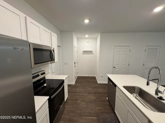 a kitchen with granite countertop a sink and a stove top oven with wooden floor