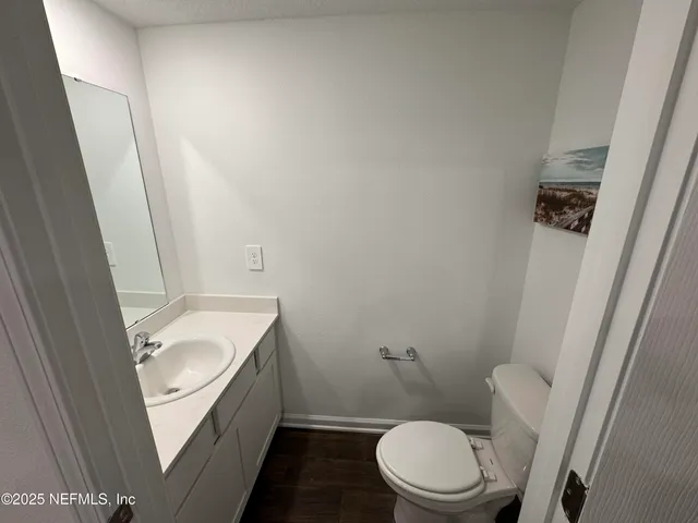 a white toilet sitting next to a white sink and vanity