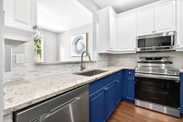 a kitchen with granite countertop a sink stainless steel appliances and white cabinets
