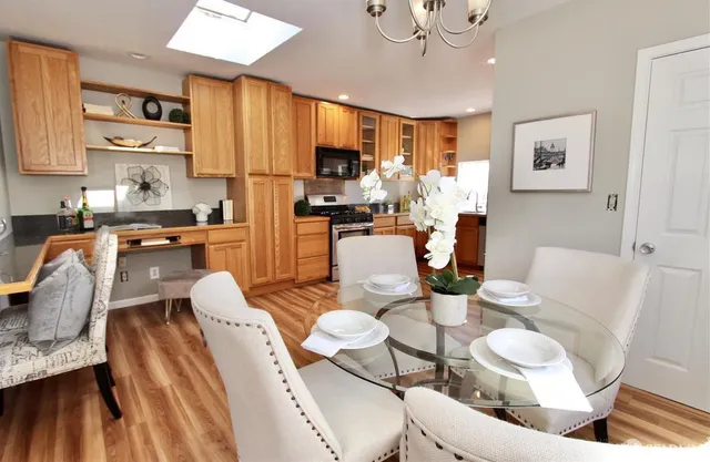 a kitchen with stainless steel appliances granite countertop a stove a sink a dining table and chairs with wooden floor