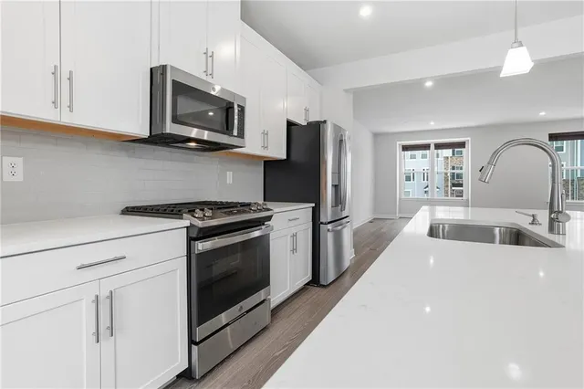 a large kitchen with stainless steel appliances granite countertop a lot of counter space and wooden floor