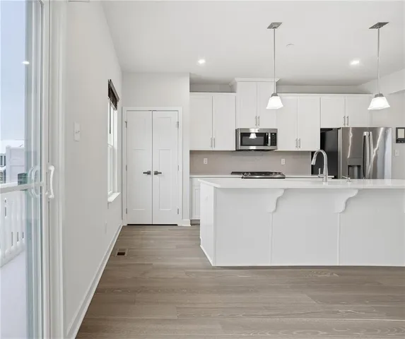 a kitchen with stainless steel appliances a large counter top a sink a refrigerator and a window