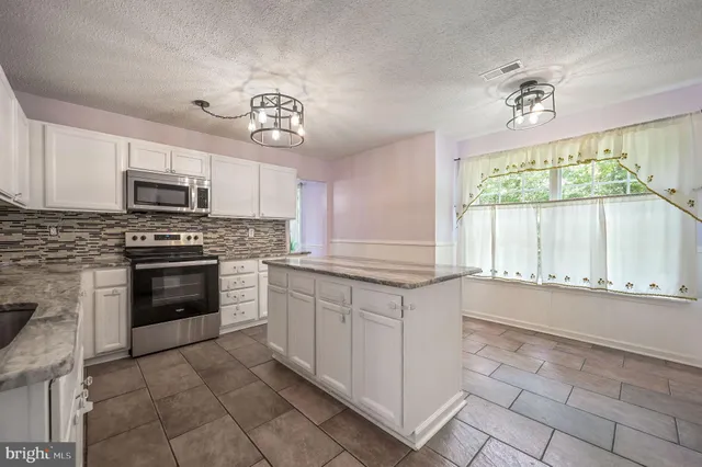 a kitchen with granite countertop a stove a sink and a microwave