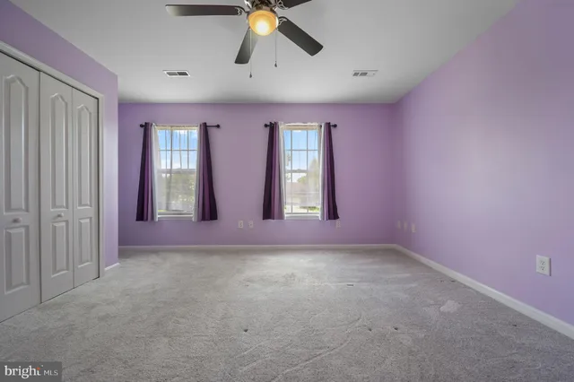 an empty room with windows and fan