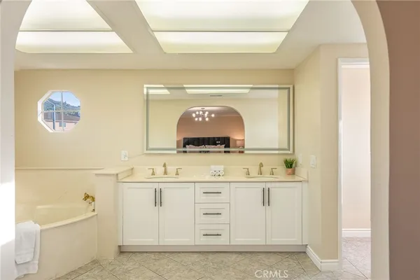 a bathroom with a double vanity sink mirror and bathtub