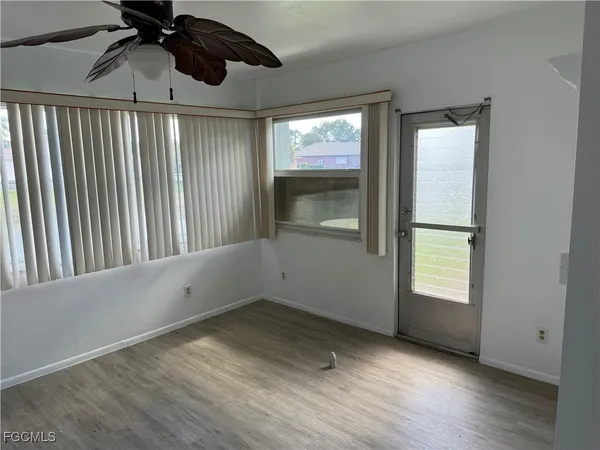 an empty room with wooden floor cabinet and windows