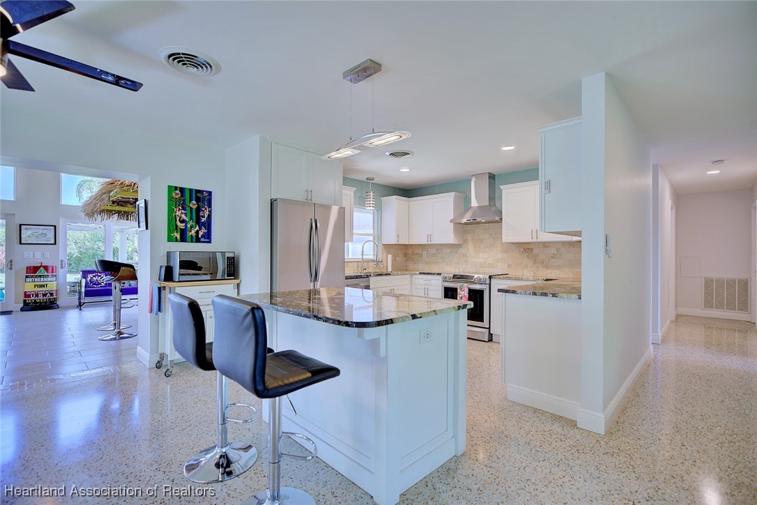 7411 Sparta Road Sebring, FL 33875 - Photo 9 of 50 a kitchen with stainless steel appliances kitchen island granite countertop a refrigerator a stove top oven a sink dishwasher and white cabinets with wooden floor